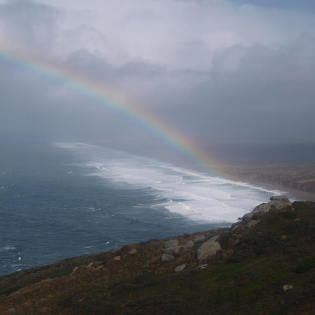 A view from the Lighthouse Visitor Center of Point Reyes Beach and a rainbow during a winter storm.