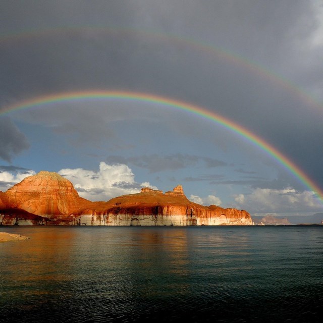 Credit: NPS Photo/ Ross Kantra On Lake Powell, a rainbow arches over the buttes in Padre Bay.