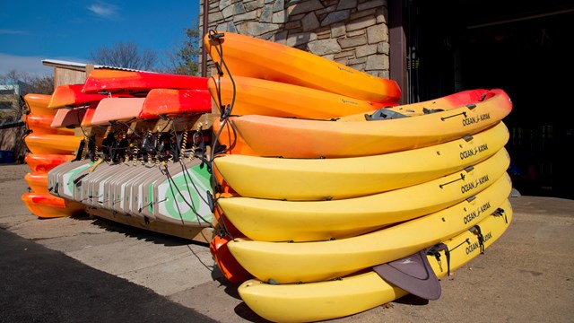 colorful kayaks, canoes and paddleboards stacked on a dock