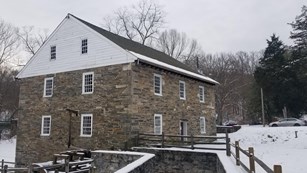 A multi story stone and wood structure.  Snow is on the ground and roof.