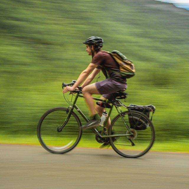 a man wearing a helmet bicycles on a path