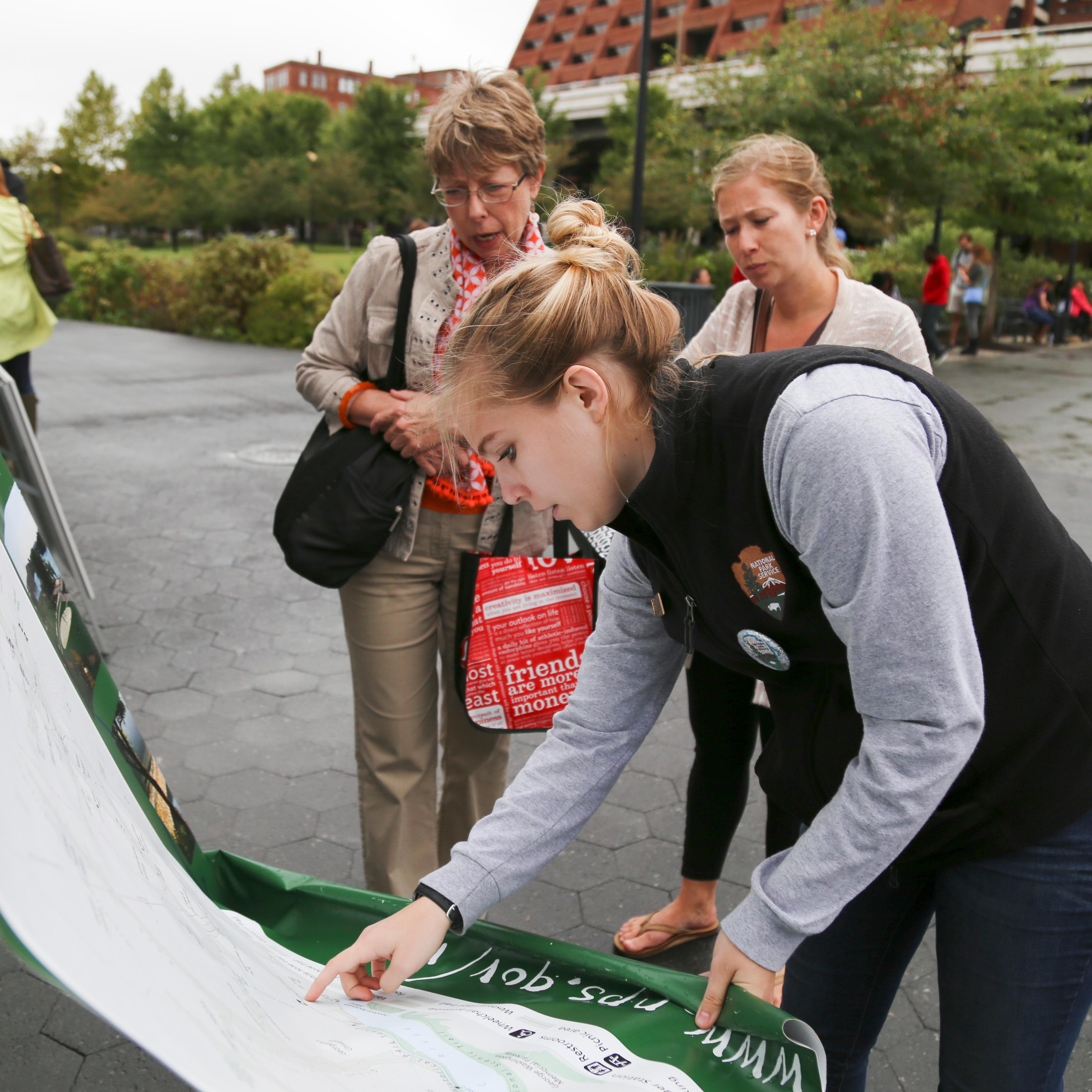 A young volunteer at Rock Creek Park shows visitors where they are on a map.