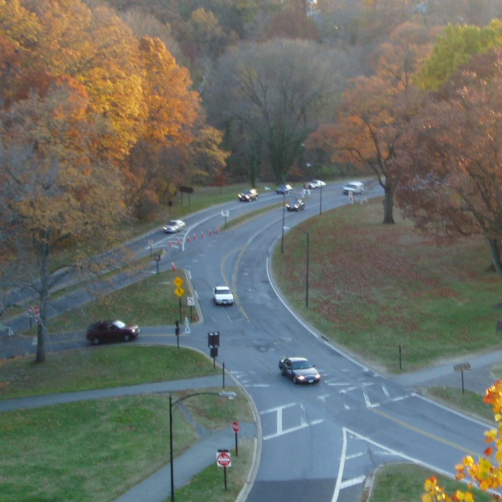 Cars driving through an intersection on a parkway with fall colors