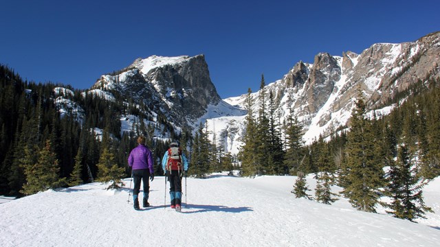 Two people are snowshoeing in winter