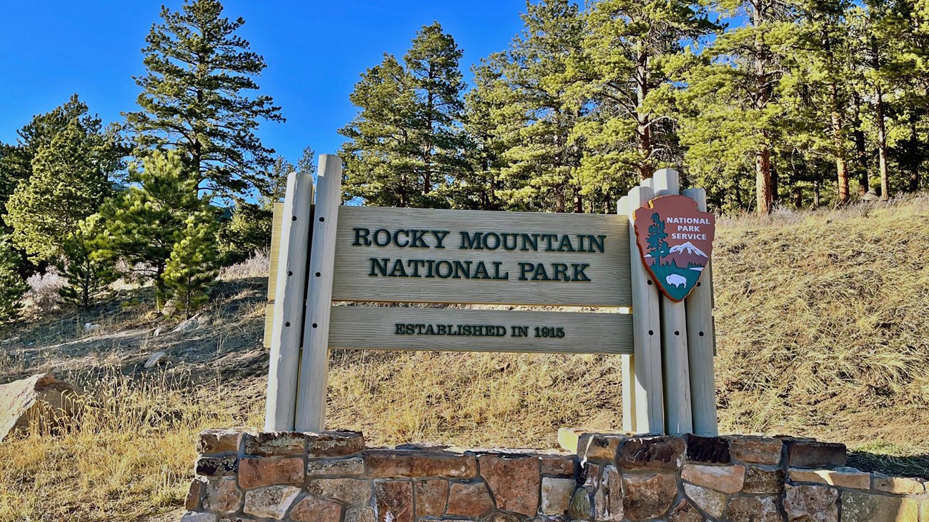 Wooden Rocky Mountain Park sign with the NPS Arrowhead