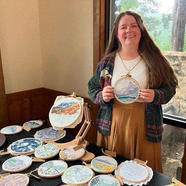 2024 Artist in Residence Kait holding a piece of embroidery