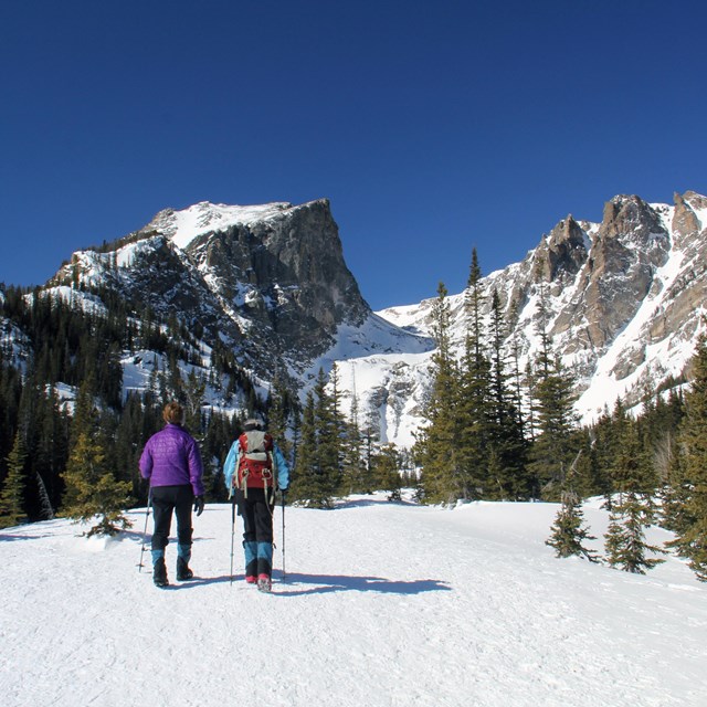 Two people are snowshoeing in winter