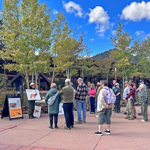 A park ranger is leading a talk outside of Beaver Meadows Visitor Center
