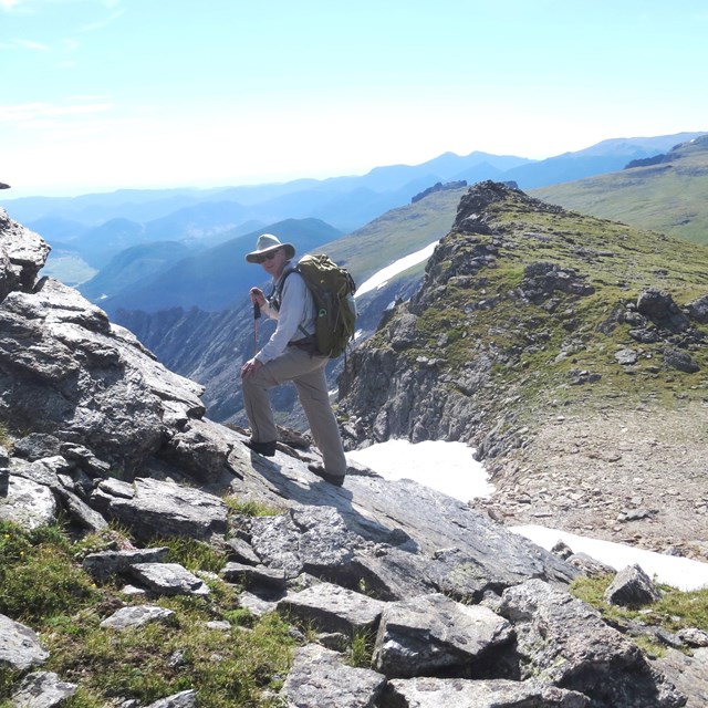 A person is wearing sun protective clothing while hiking in the alpine