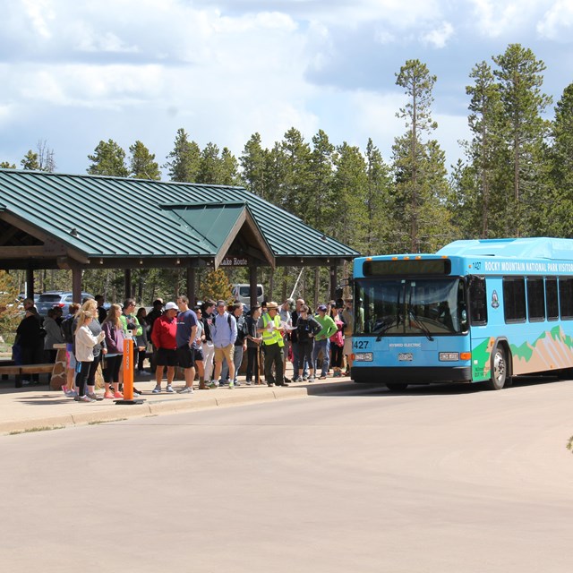 Visitors are in line and boarding the park's hybrid shuttle bus