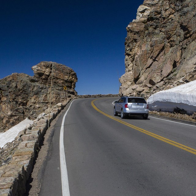 A vehicle is driving on Trail Ridge Road near Rock Cut