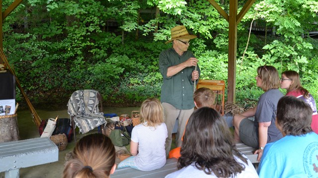 Visitors listen as a speaker discusses prehistoric weapons.
