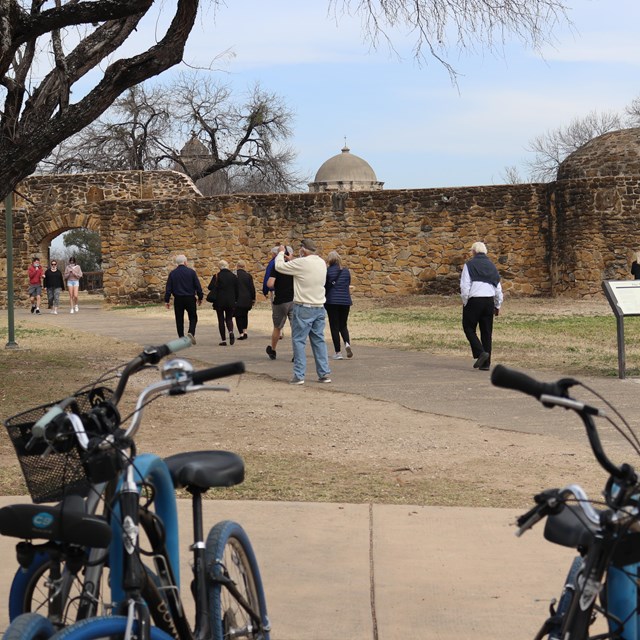 Visitors walking into the park, and bicycles in the foreground. 