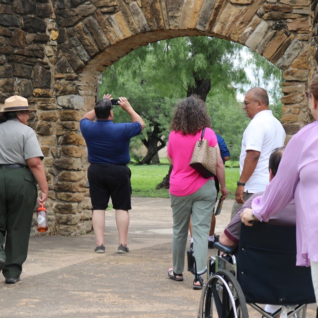 A group of people walk with a ranger. One of the people is in a wheelchair.