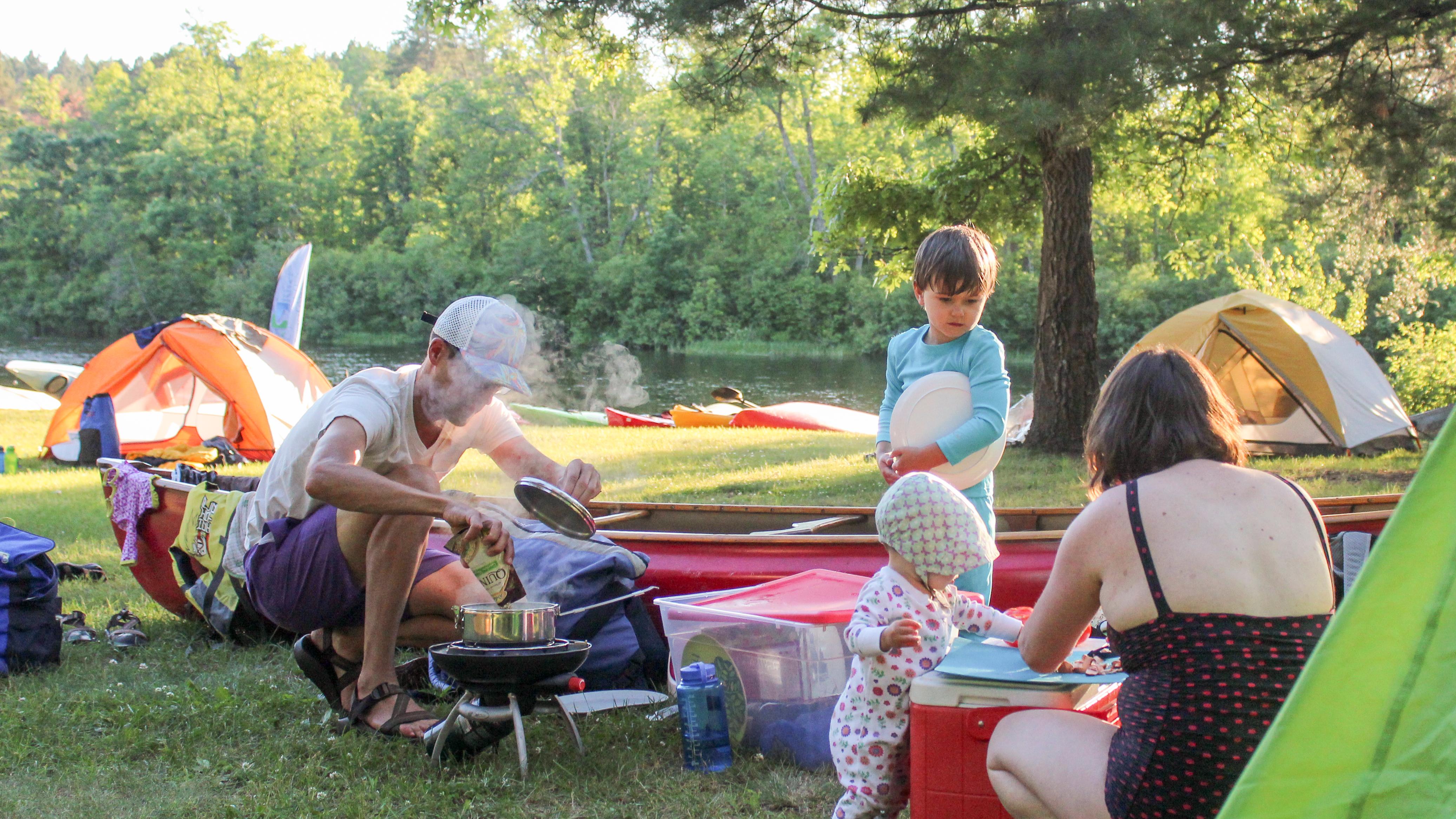 A family cooks outdoors at their campsite,