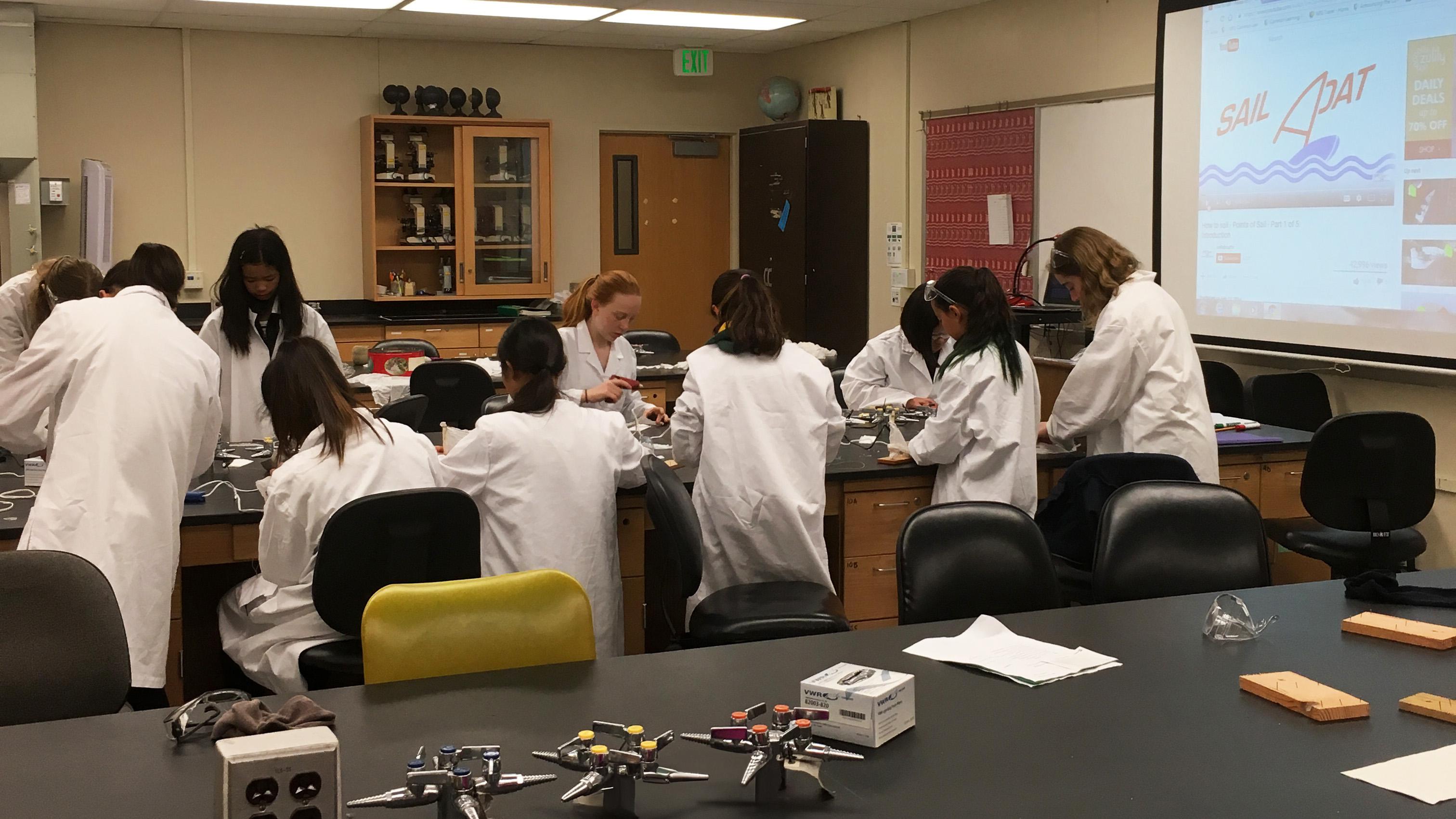 children wearing white lab coats in a classroom