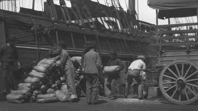 historic photo of a group of Chinese men loading cargo onto a ship