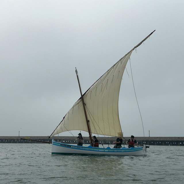 people pull lines on a sailboat in Aquatic Cove with misty weather around them