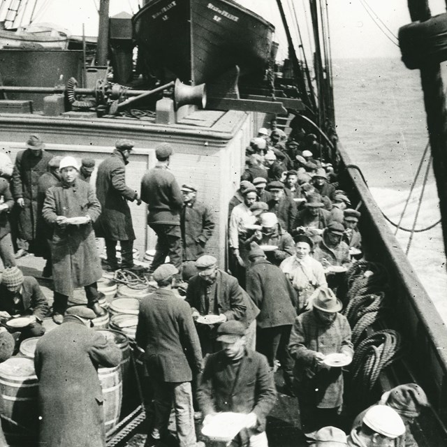 black and white photo from 1918 of fishermen eating dinner on the deck of a ship