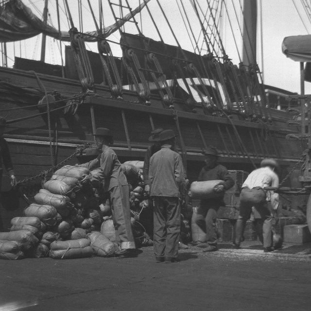 historic photo of a group of Chinese men loading cargo onto a ship