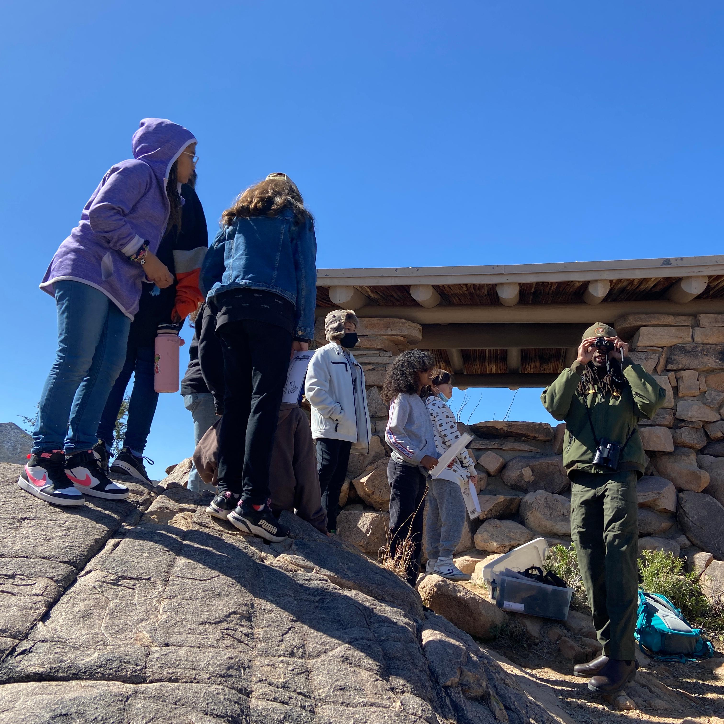 ranger and students with binoculars