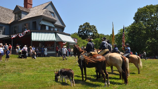 Rough rider impersonators mounted on horses outside of the Theodore Roosevelt home