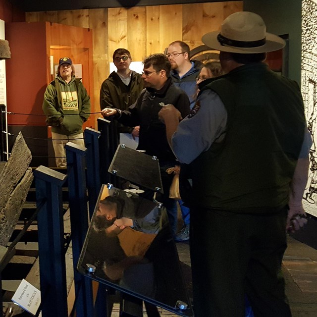 park ranger talks to a group of visitors in front of artifact display