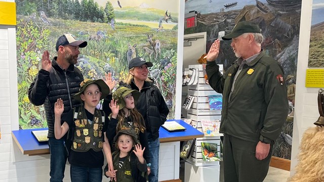 A family raises their hand as they take the junior ranger pledge.