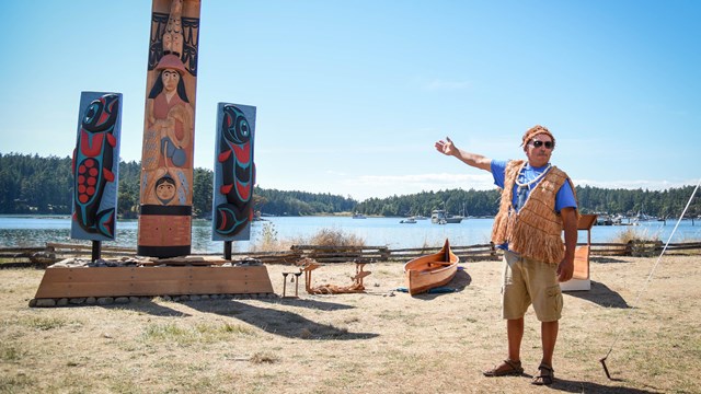 A Coast Salish tribal member presents artistic story poles at English Camp.