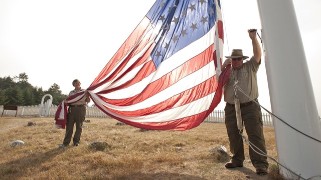 Two park volunteers raise the American flag