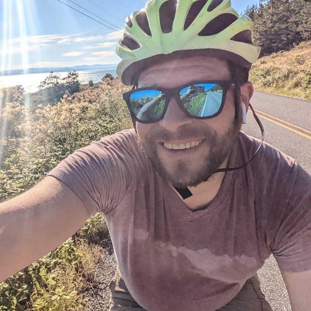 Man taking a selfie on a bike, wearing a bike helmet and sunglasses