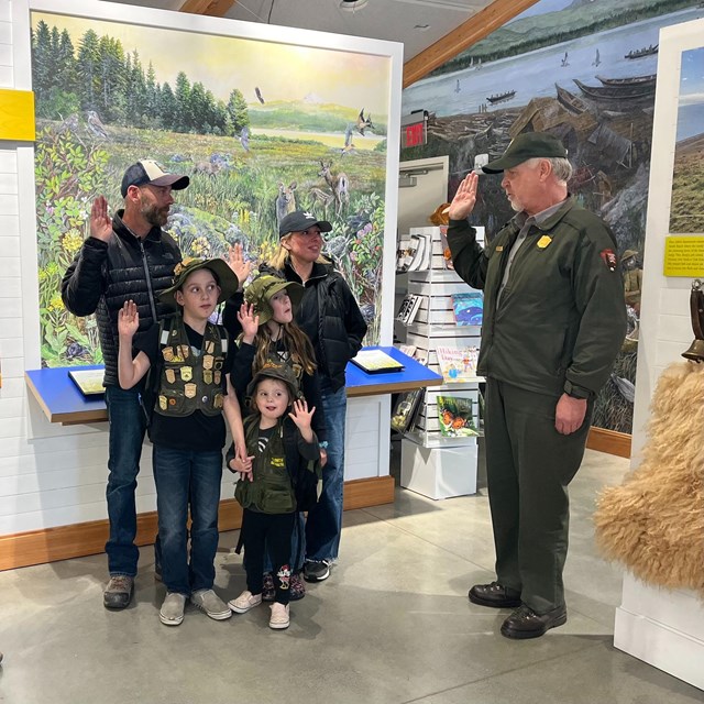 A family raises their hand as they take the junior ranger pledge.