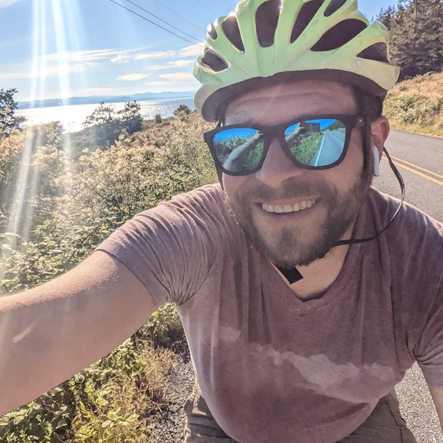 a man takes a selfie on his bike, he is wearing a helmet