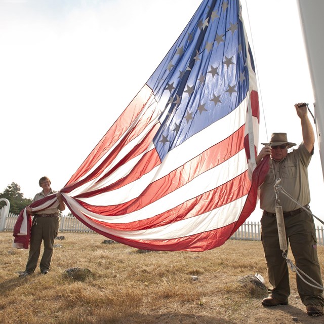 Two park volunteers raise the American flag