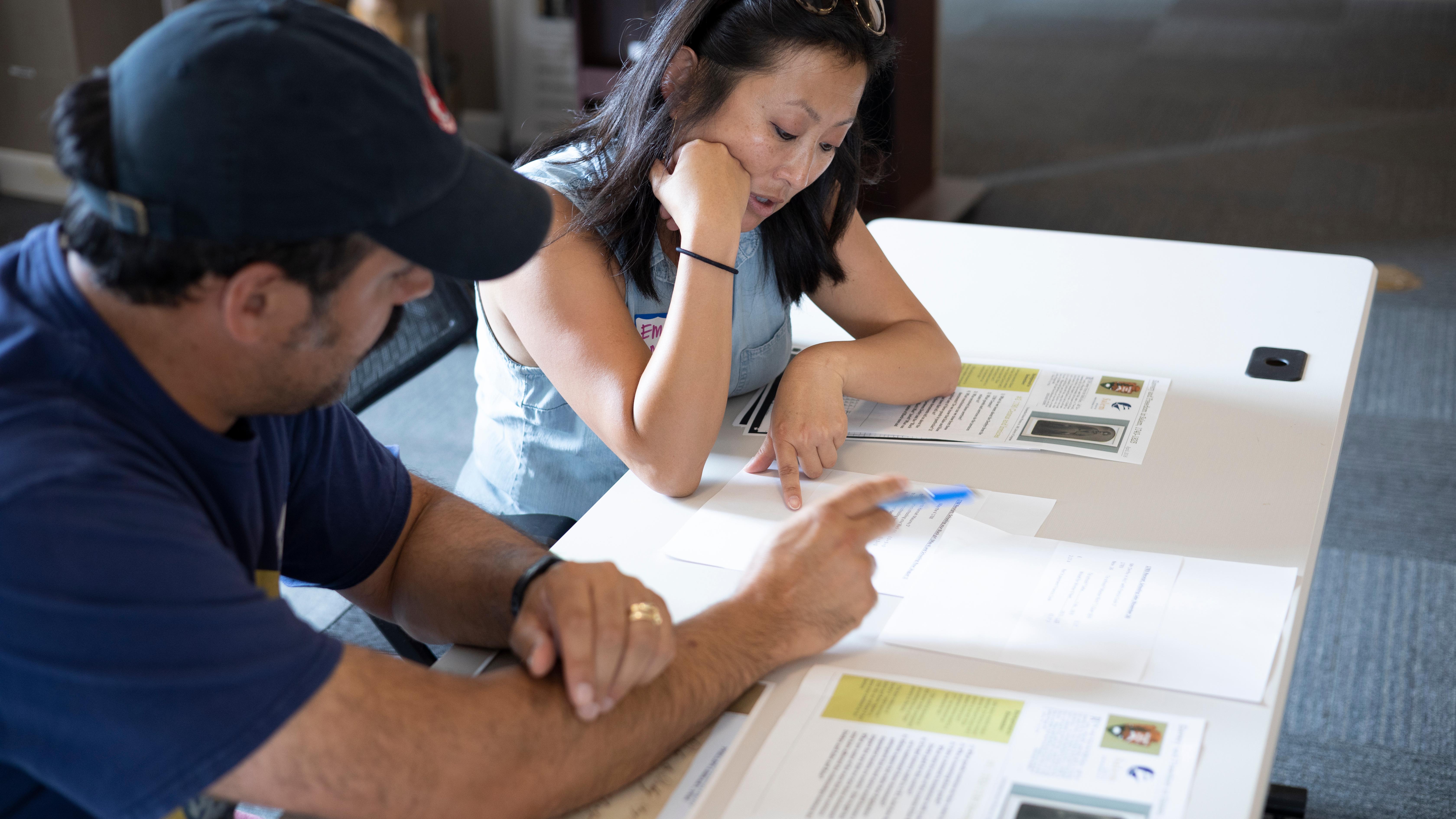Two people sit at a desk reviewing primary source documents.