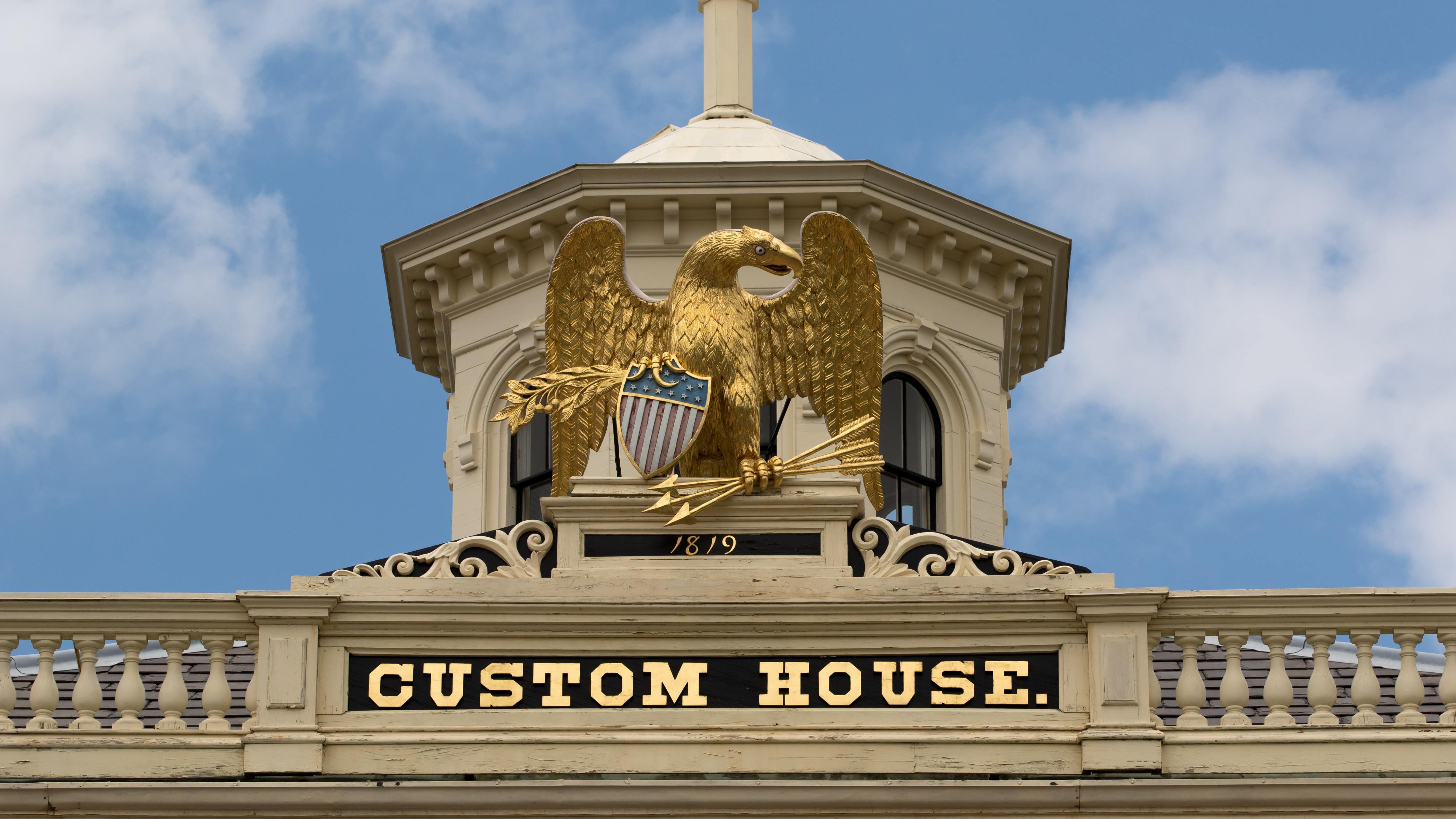 A statue of a golden eagle on the top of the Custom House