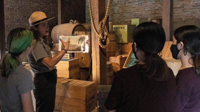 A park ranger holding an historic image speaks to young people.