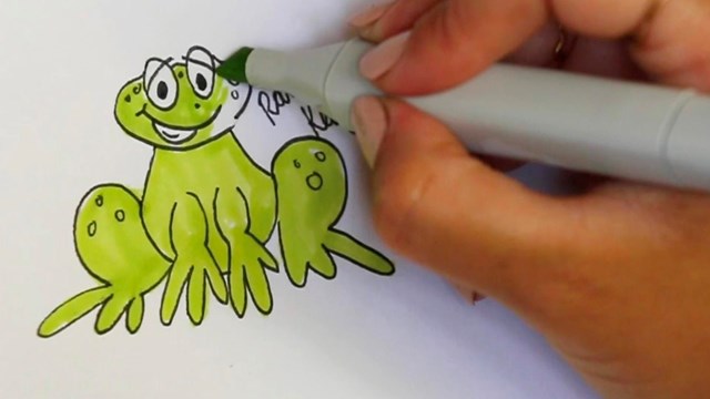 Close up of hand holding a marker drawing a illustration of a frog.