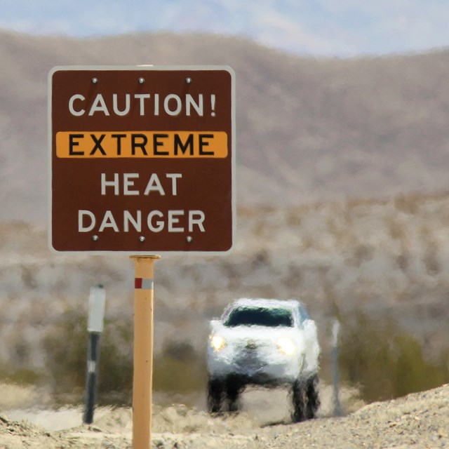A truck drives across a sandy road as heat shimmers
