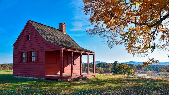 A small red farmhouse sits on a hill.