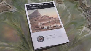 A Scotts Bluff Junior Ranger booklet rests on a relief map of the monument. 