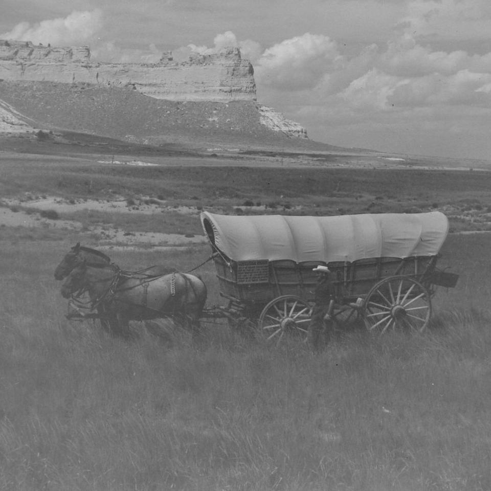 old black and white photo of a wagon pulled by horses