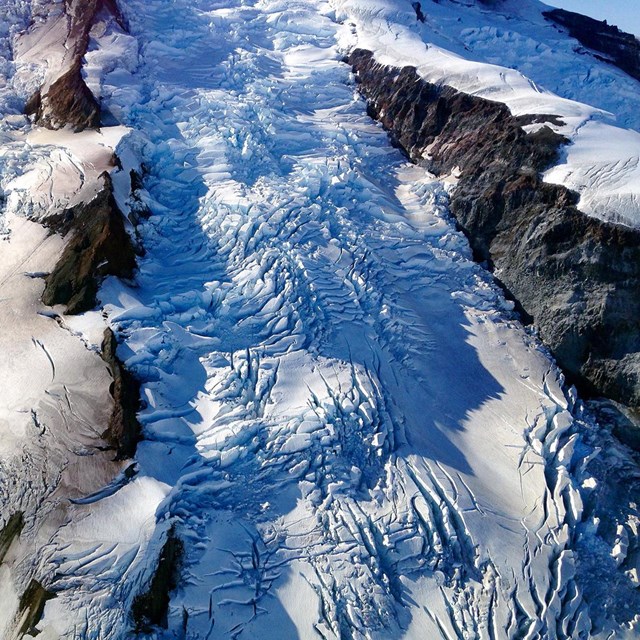 A close-up view of the surface of a glacier with ice and rocky morraine.