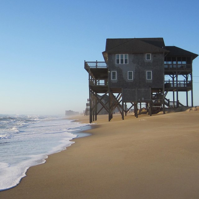 House on stilts on edge of water on the beach