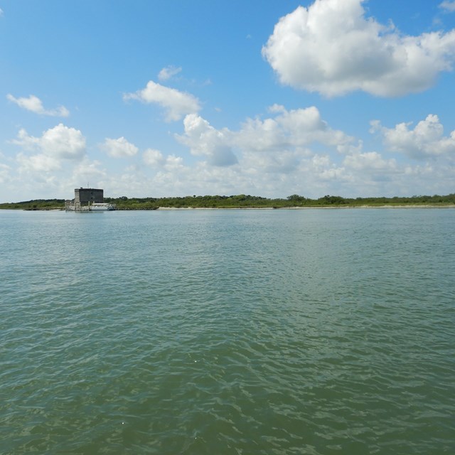 Water with tall fort on the other shoreline