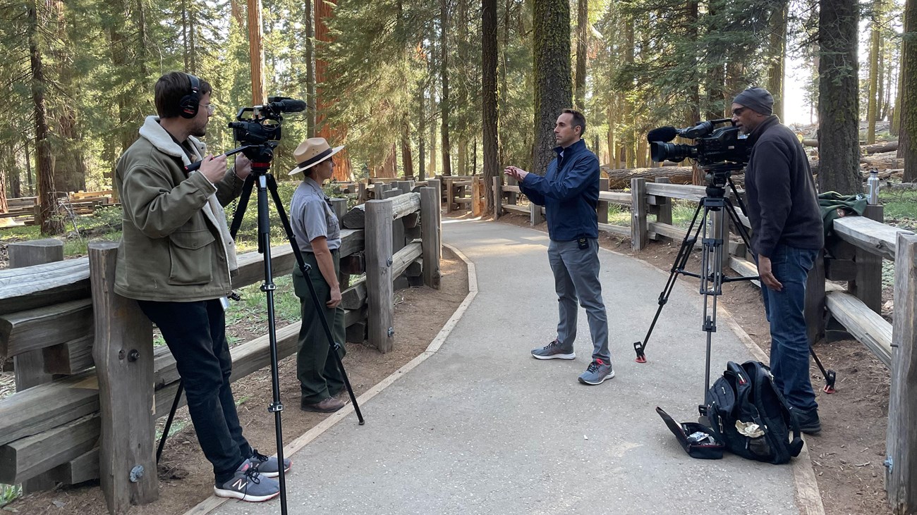 People with video camera film a National Park Service ranger being interviewed.