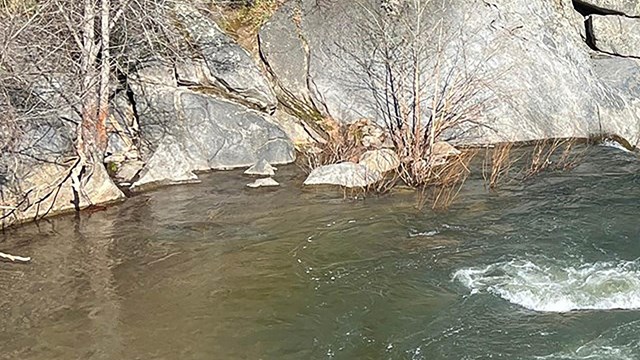 A river switftly flows with mountains in the background