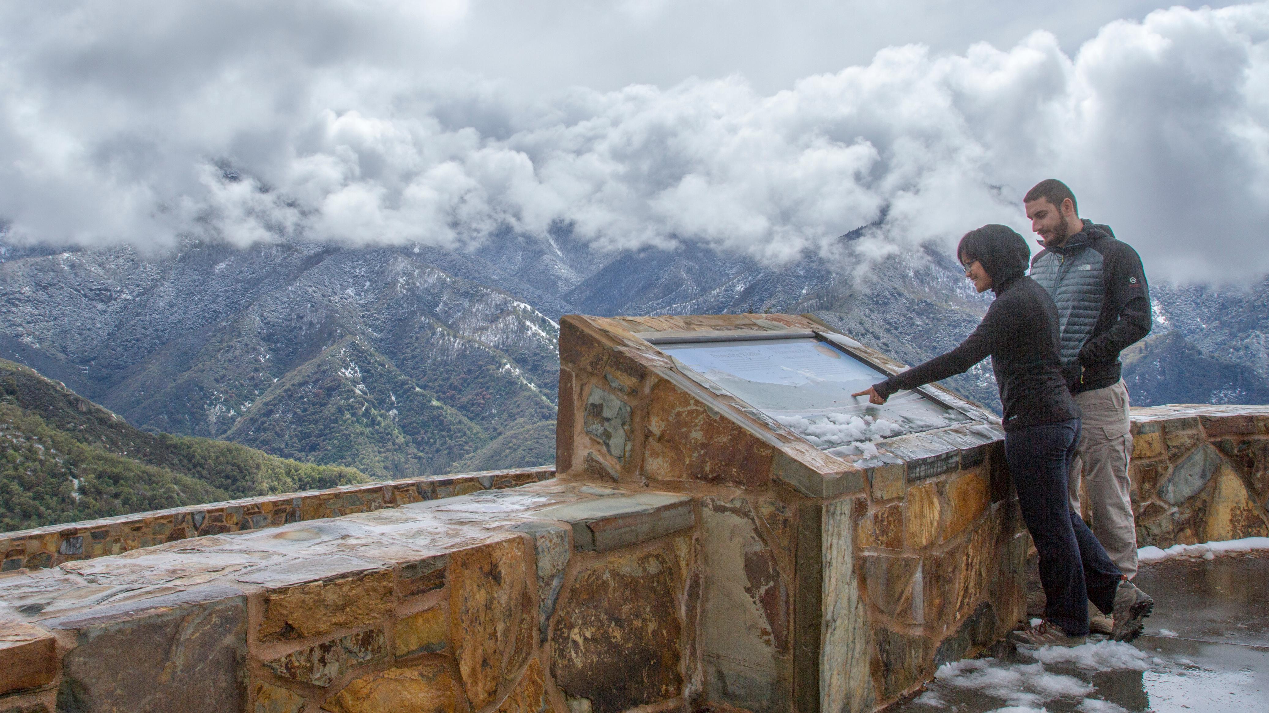People read an exhibit at a snowy viewpoint. Photo by Kirke Wrench.