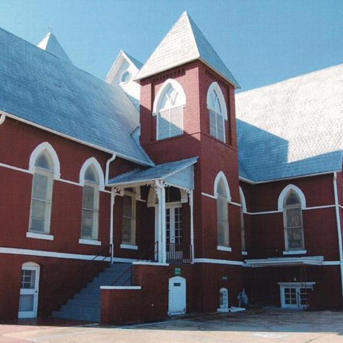 A large red brick building with a set of stairs to the front door.