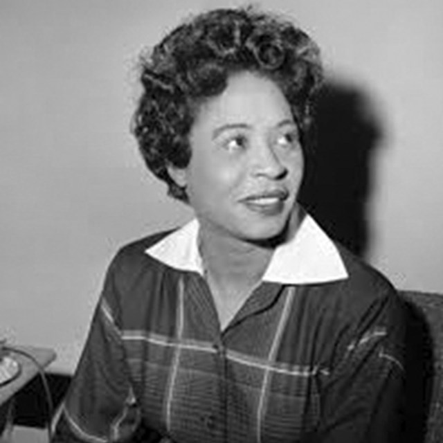 Black and white photo of a young black woman looking to the side with a smile on her face.
